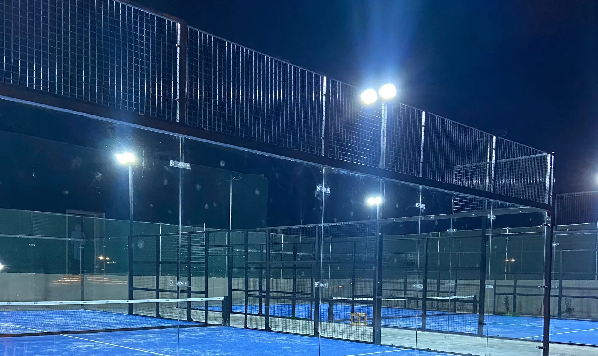 Baseline Courts' glass-walled padel courts under floodlights at night