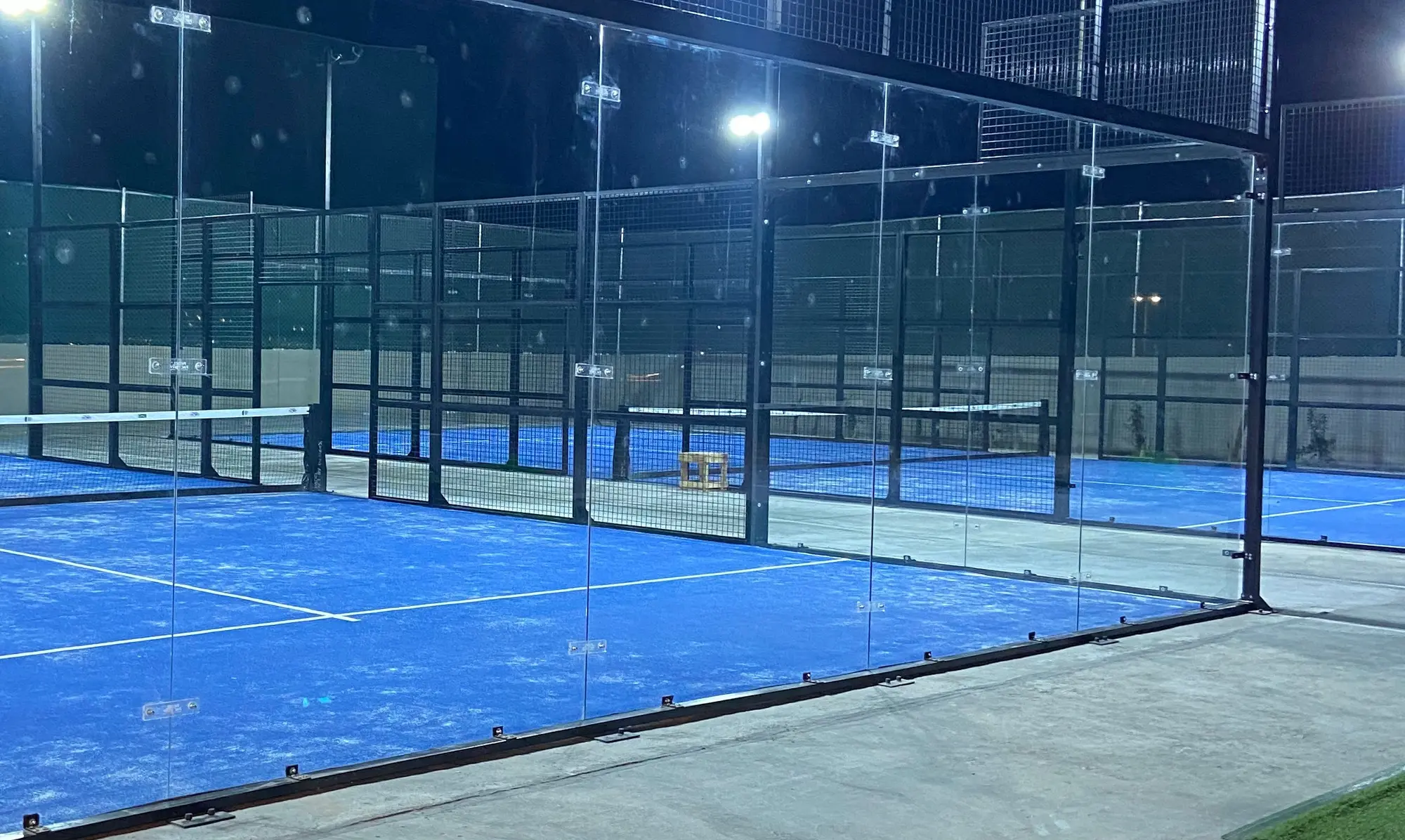 Glass-walled courts lit up at night at Baseline Courts