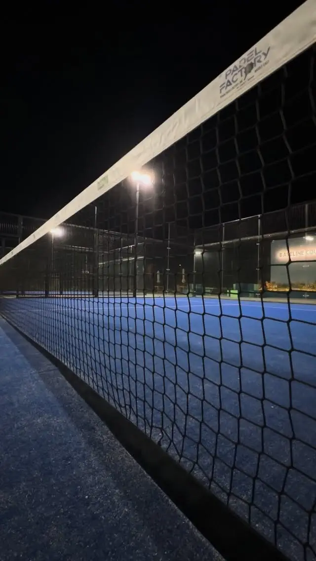 The net of a Baseline Courts court under floodlights at night
